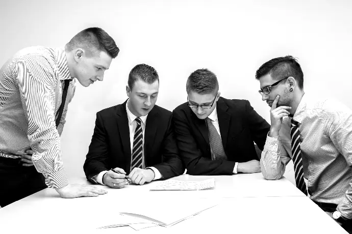 four men looking to the paper on table