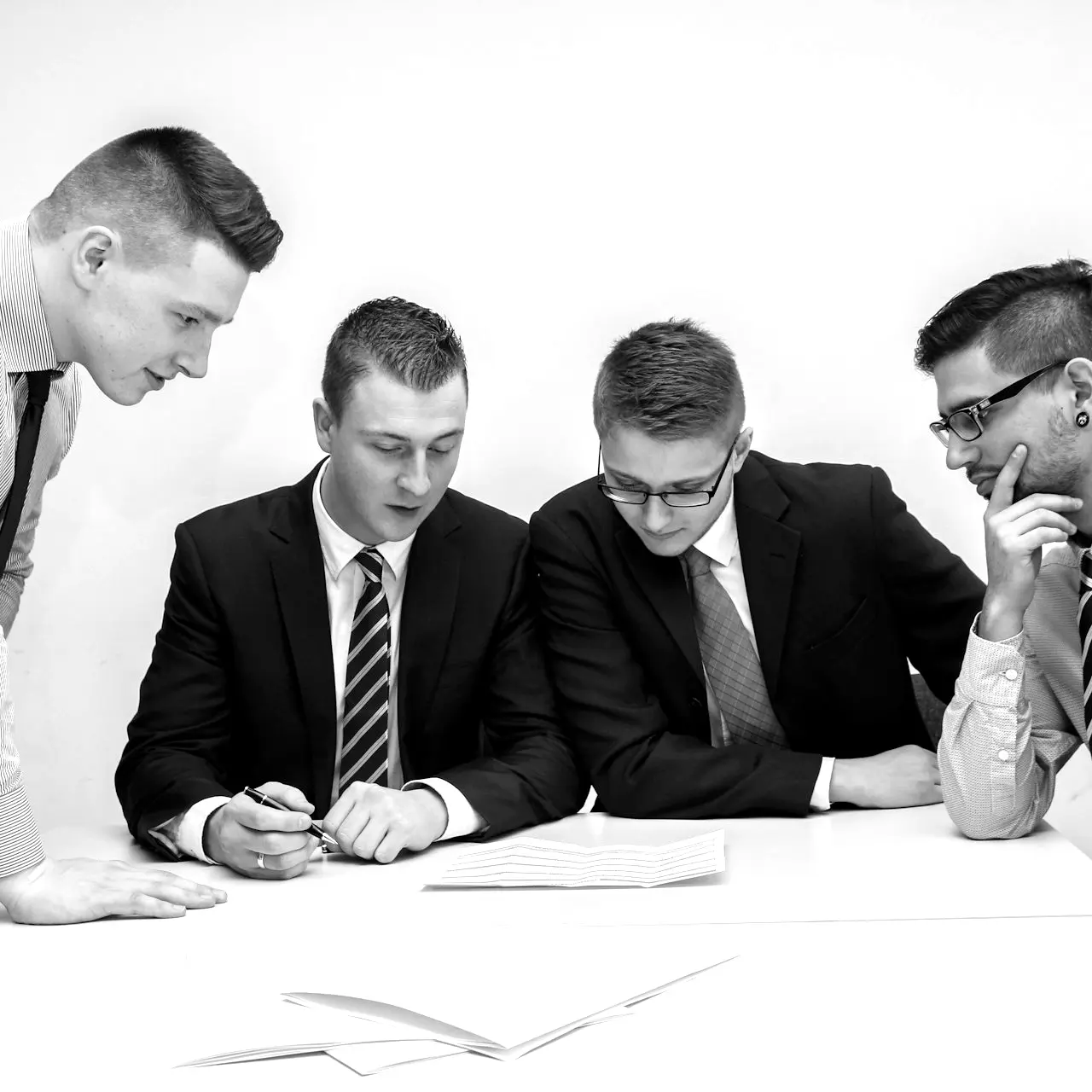 four men looking to the paper on table
