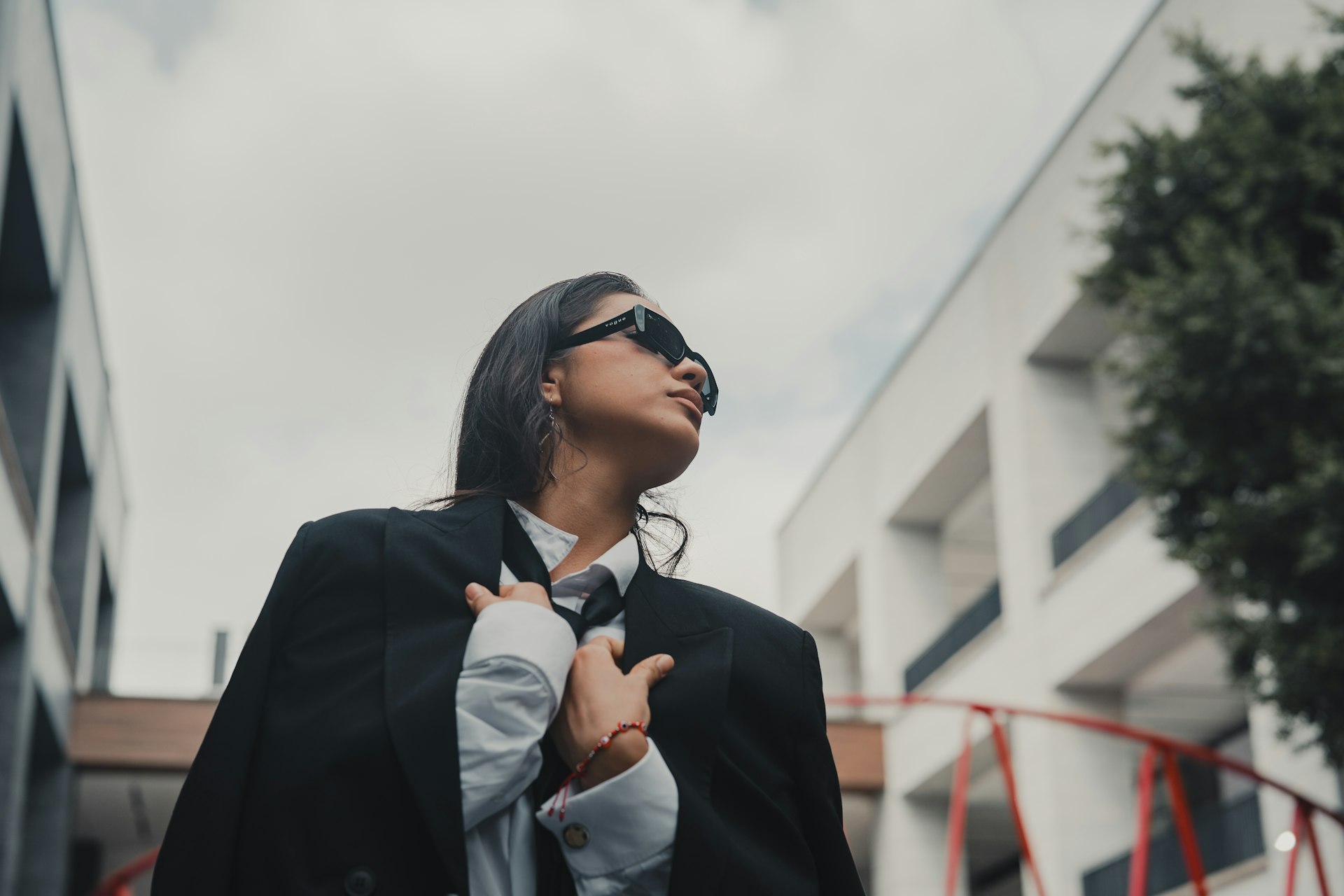 A woman wearing a suit and tie standing in front of a building